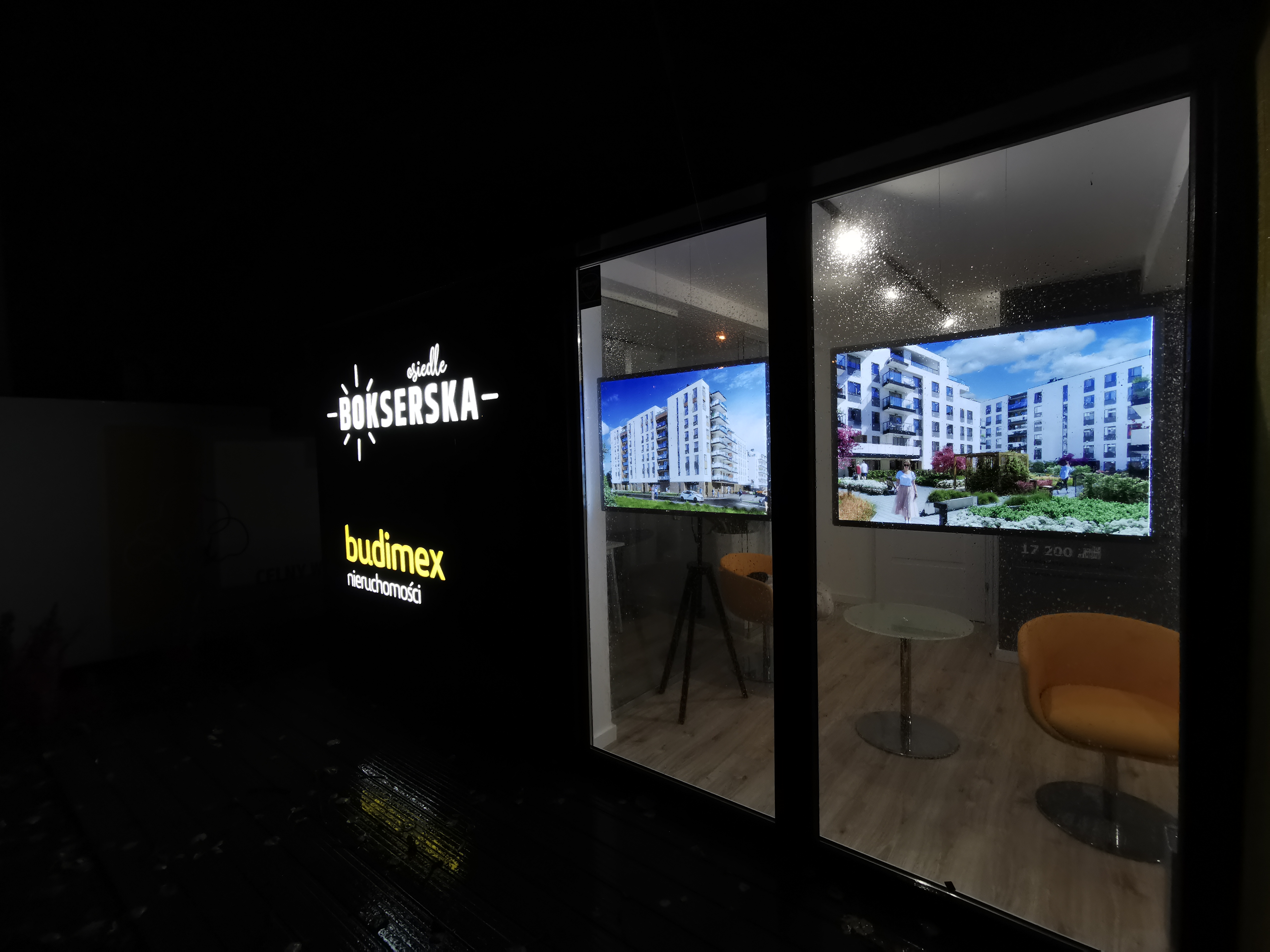 Systemy linkowe z ekranami LED prezentujące ofertę dewelopera w witrynie biura sprzedaży, widoczne wieczorem